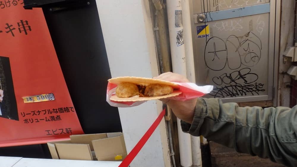 「たこせん」を右手で持って中のたこ焼きを見せている写真