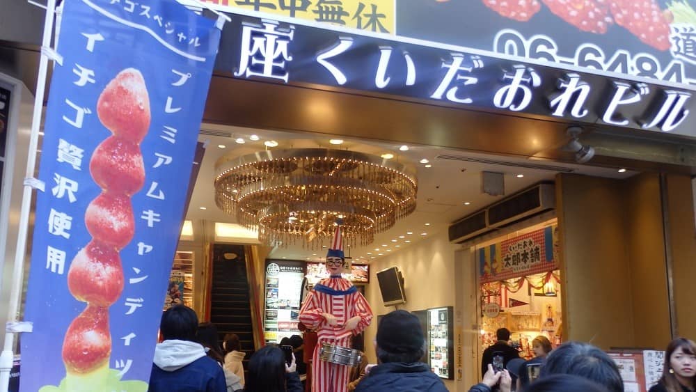 くいだおれビル入り口にあるくいだおれ人形を多くの方が写真を撮っている写真