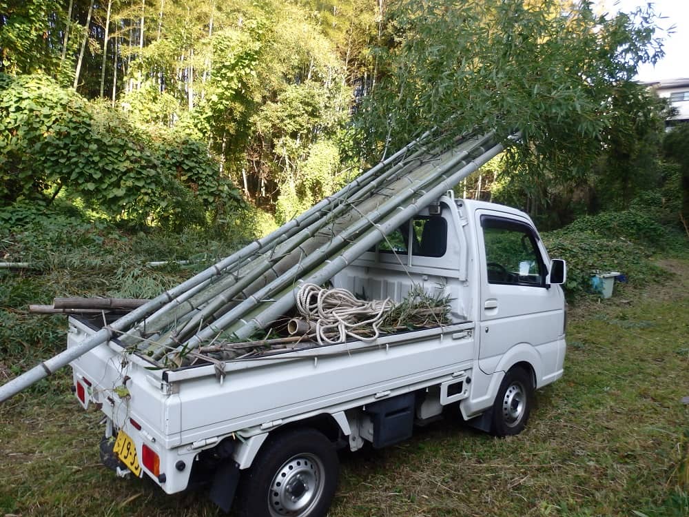 寸法切りした竹を軽トラに積み込んでいる写真